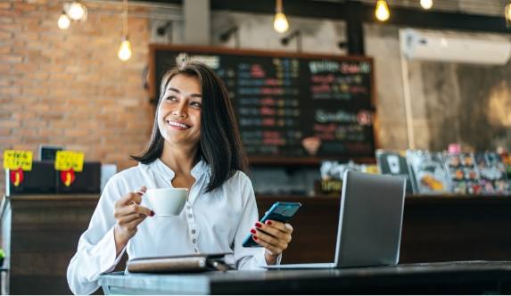 woman-sitting-happily-working-with-smartphone-coffee-shop-notebook